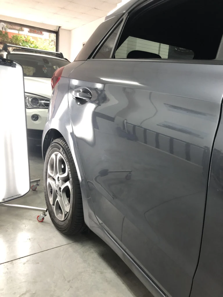 Varillero sacabollos trabajando en la chapa lateral de coche para eliminar abolladuras con método PDR