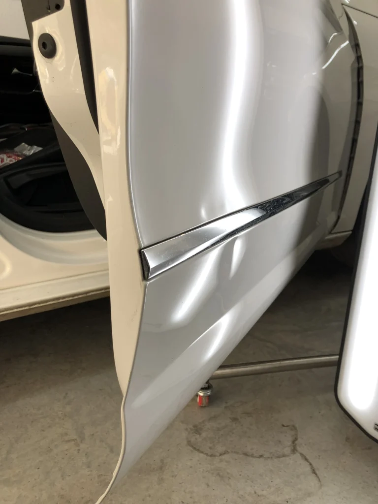 Varillero sacabollos reparando la chapa de la puerta del coche para eliminar abolladuras mediante método PDR profesional.