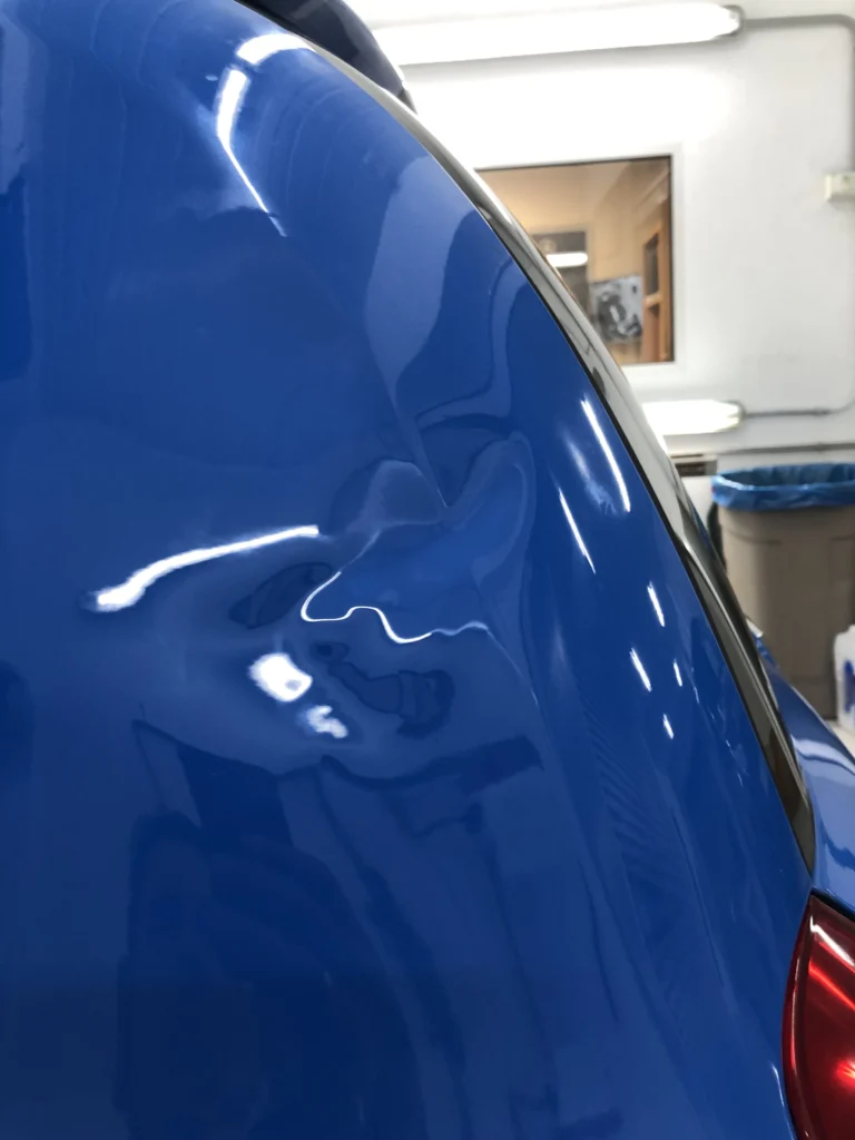 Varillero sacabollos trabajando en la chapa del maletero de coche para eliminar abolladuras con técnica PDR sin pintura.