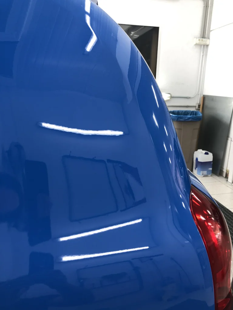 Varillero sacabollos trabajando en la chapa del maletero de coche para eliminar abolladuras con técnica PDR sin pintura.