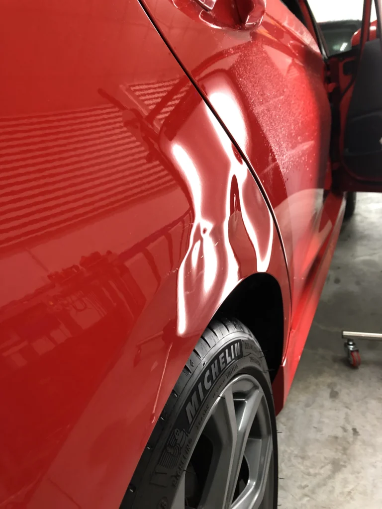 Varillero sacabollos trabajando en la chapa lateral de coche para eliminar abolladuras con método PDR